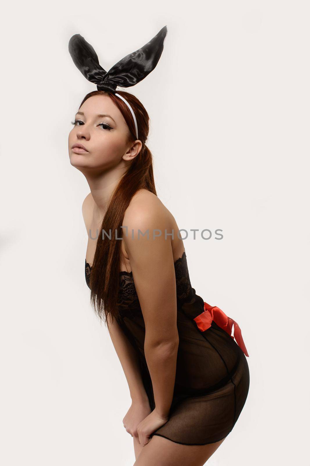 Sexy play girl wearing a bunny costume posing against isolated white background