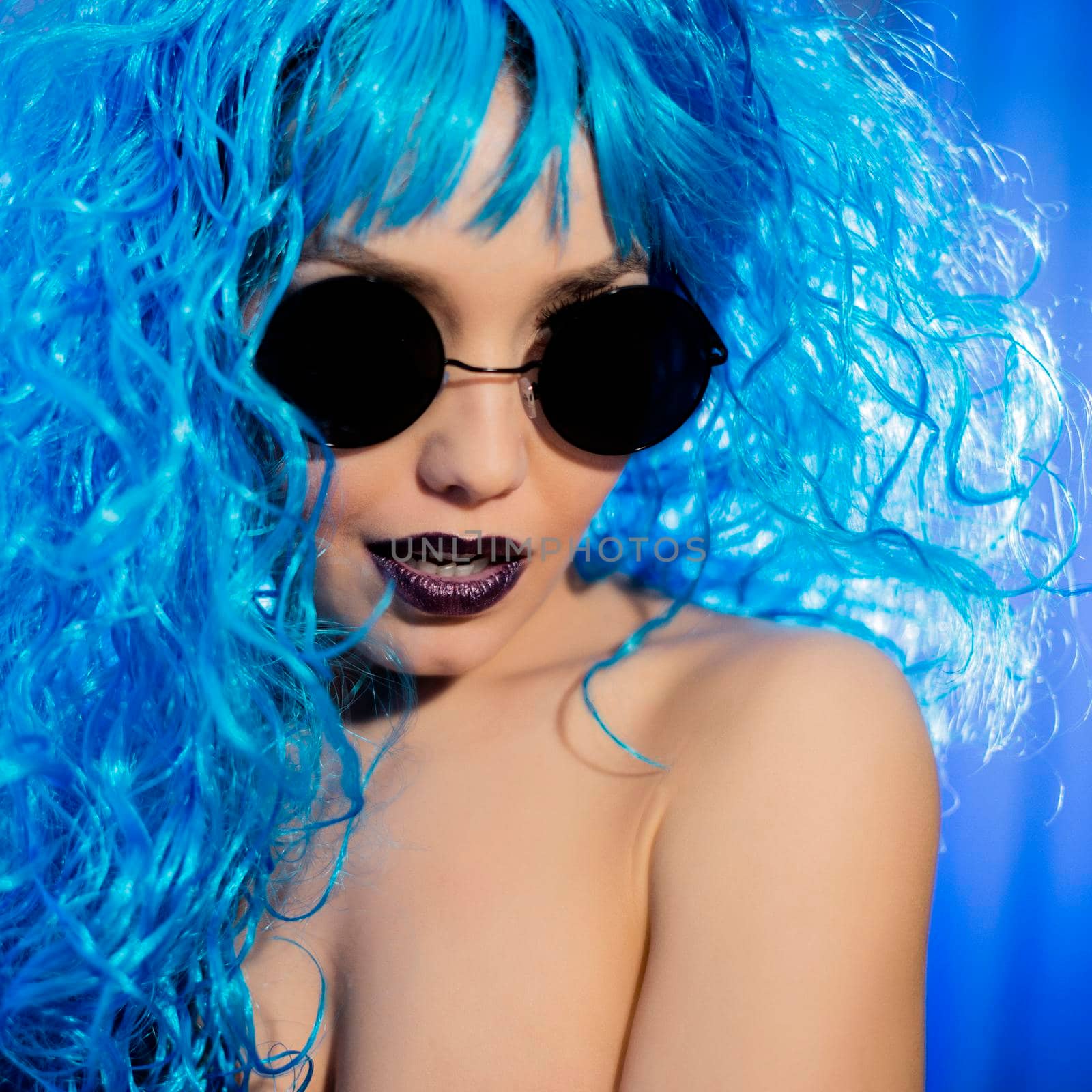 Colorful portrait of an attractive young woman with sunglasses and blue hair