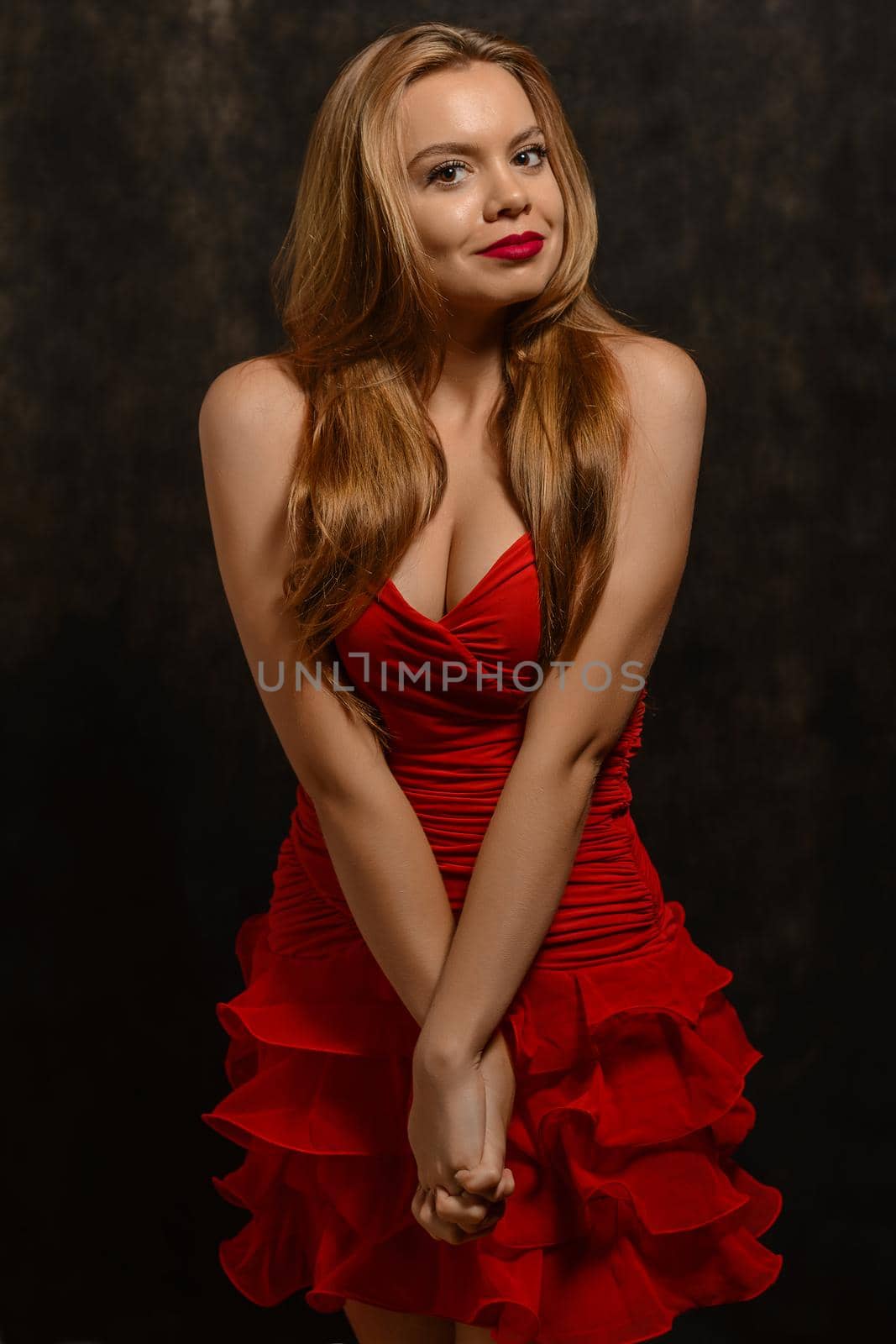 Beautiful blond woman in elegant red dress. Professional makeup and hairstyle