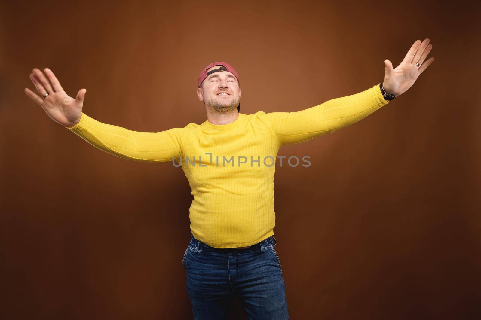 Caucasian plump middle-aged man dancing in the studio on a brown background. Studio portrait.