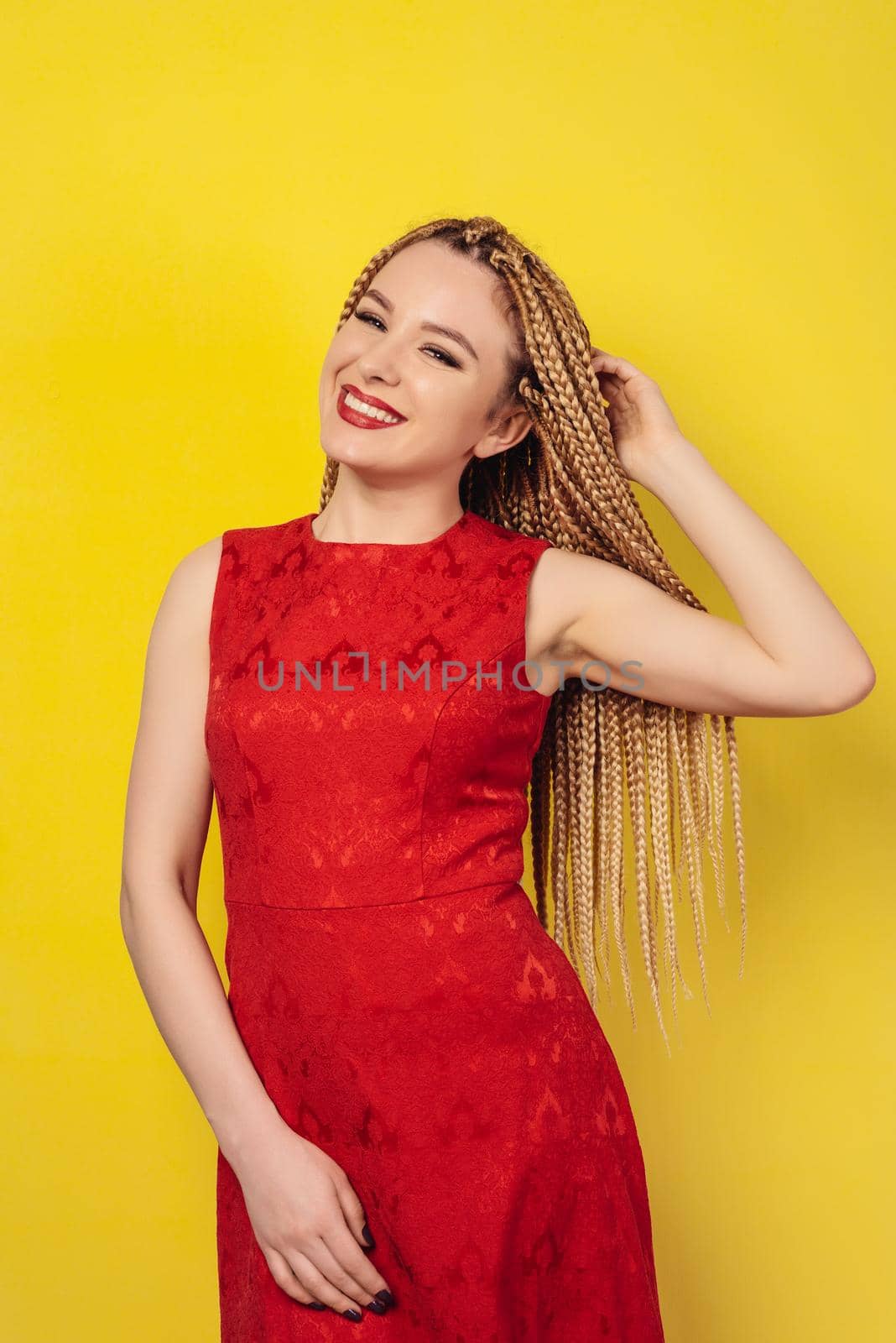 cheerful beautiful young woman dressed in a red dress, holds pigtails. studio shot