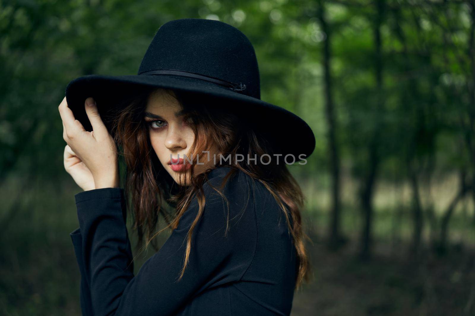 woman in black dress in the forest Halloween Witch costume. High quality photo