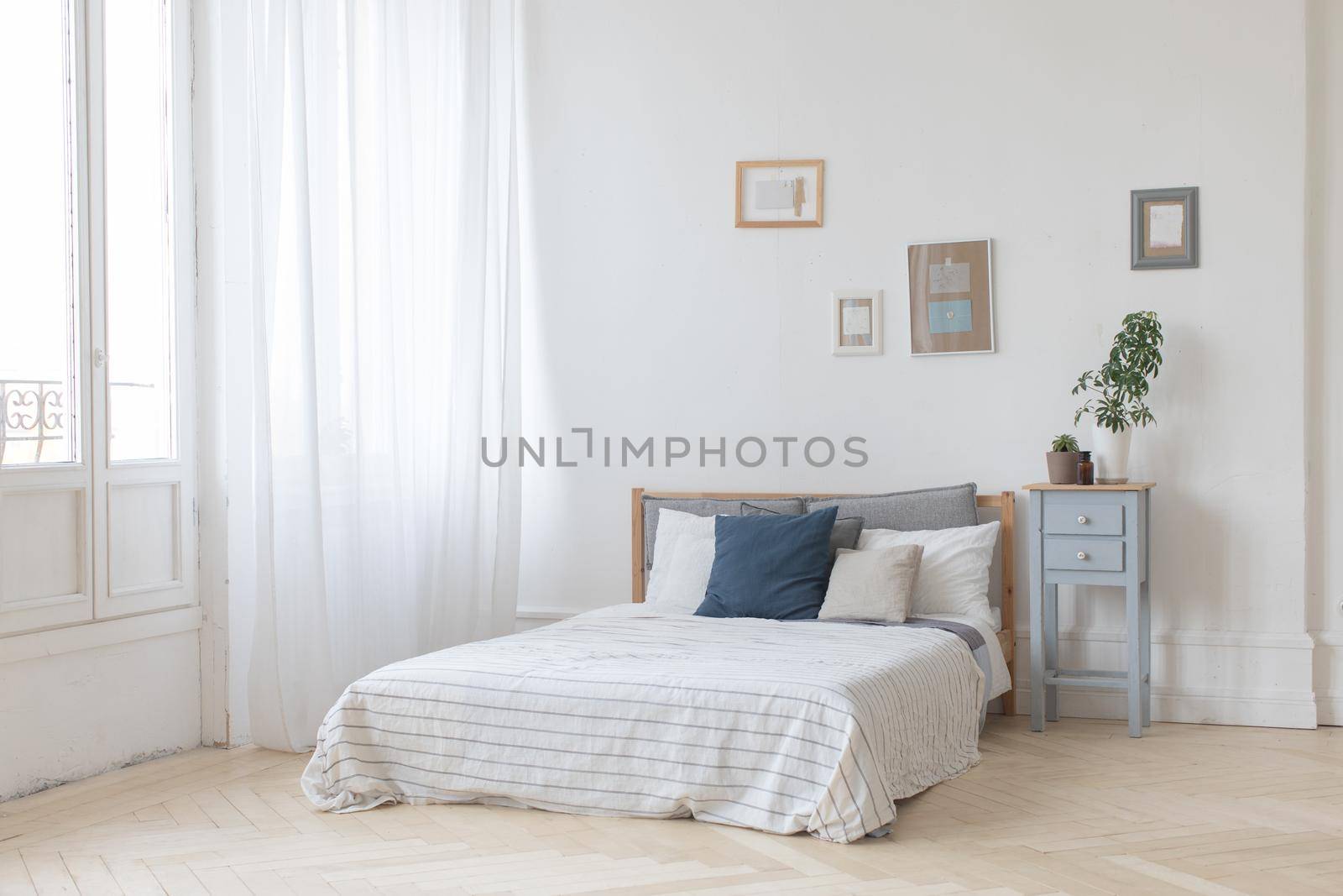 Interior of white and gray cozy bedroom with plants on the bedside table