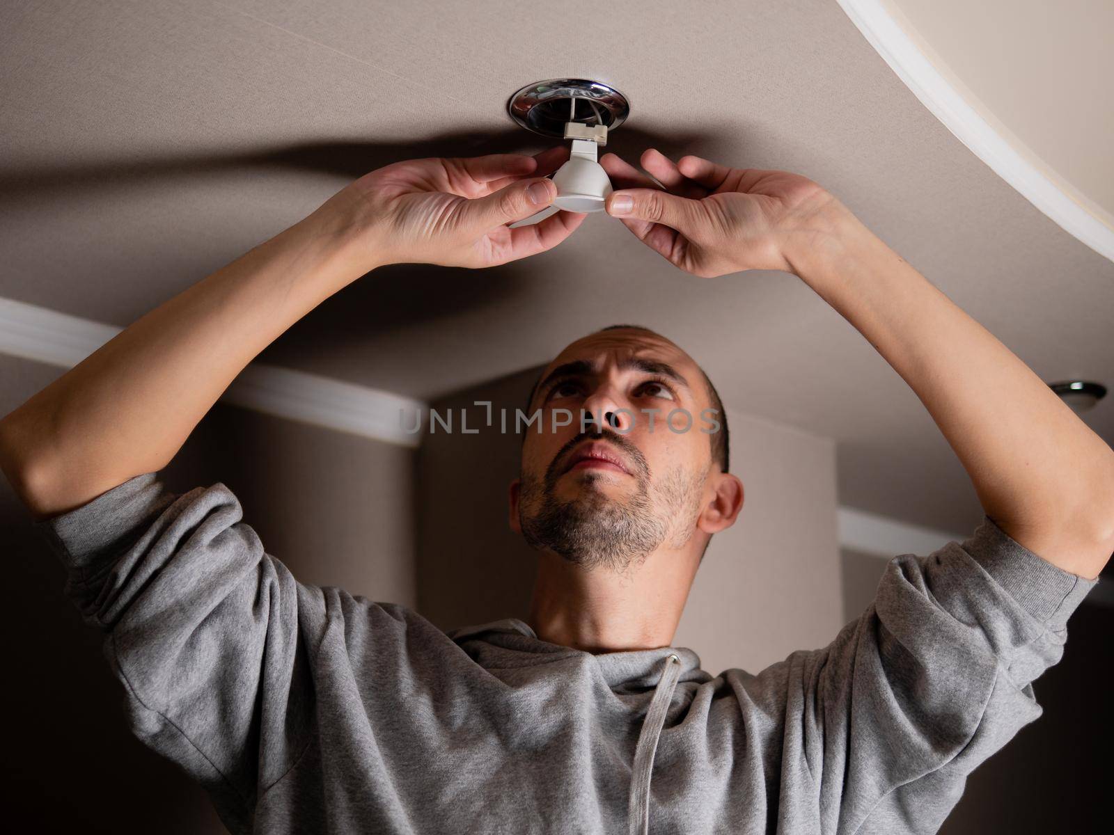 The man unscrews a broken old lamp. Installation of ceiling lighting.