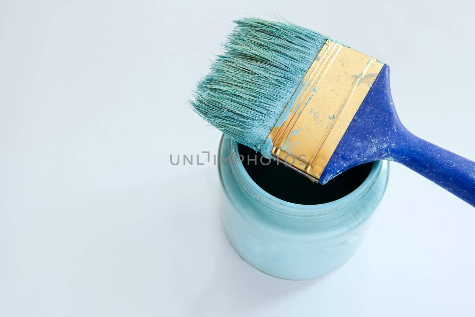 Brush and blue paint jar with a close-up on a white background. brush and paint jar with blue paint