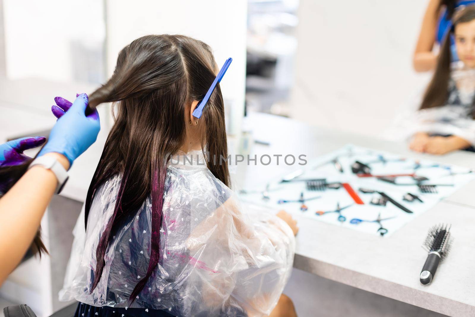 hairdresser dyes hair for a little girl in a hair salon. Dyed, bleached hair