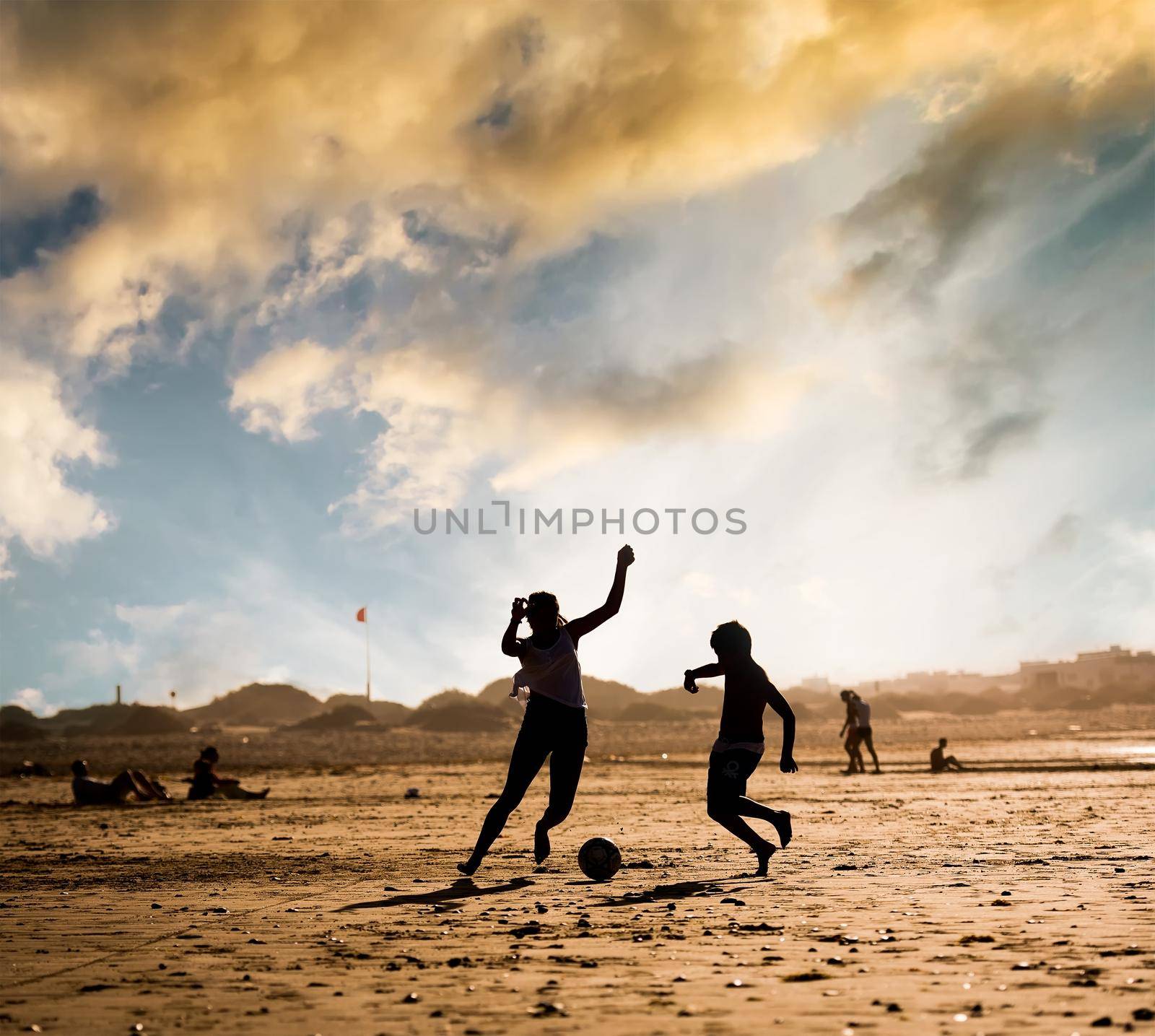 Silhouette of children on the beach with a ball at sunset