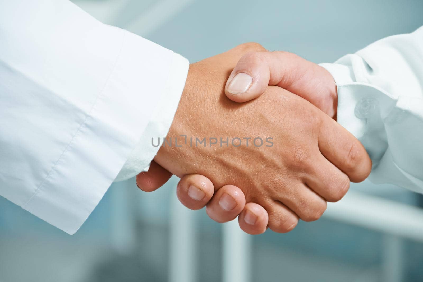 Man doctor shakes hand with another doctor in hospital, concept of teamwork