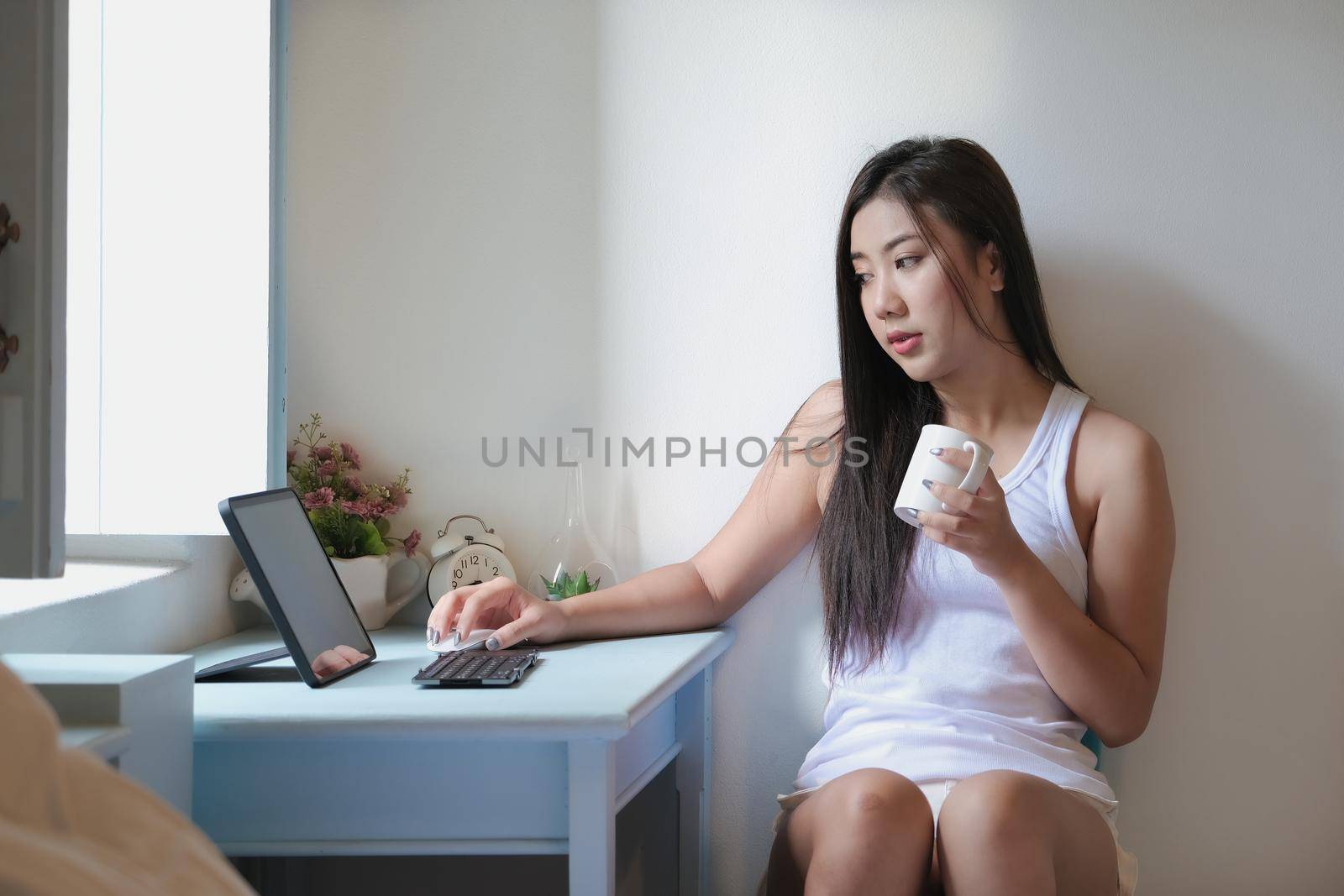 new normal, a businesswoman using tablet to work for a company Via the internet on your desk at home. by Manastrong