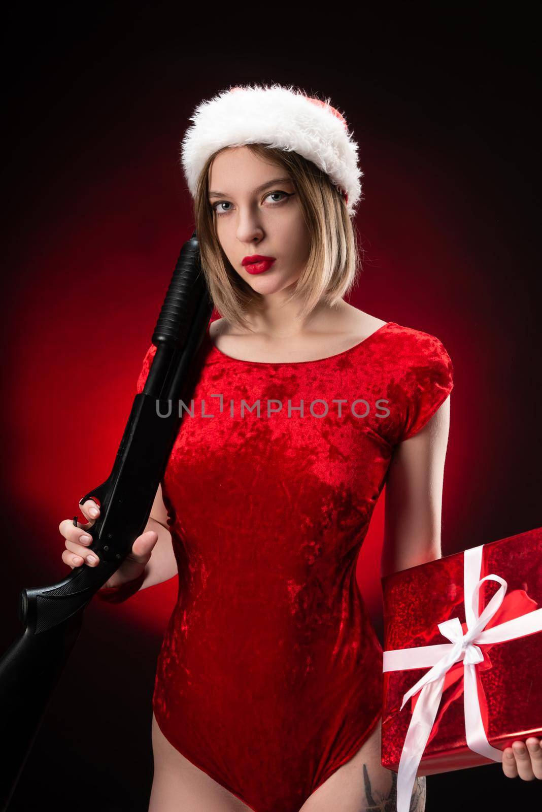 girl in a red bodysuit and a Santa Claus hat with a shotgun in her hands for Christmas