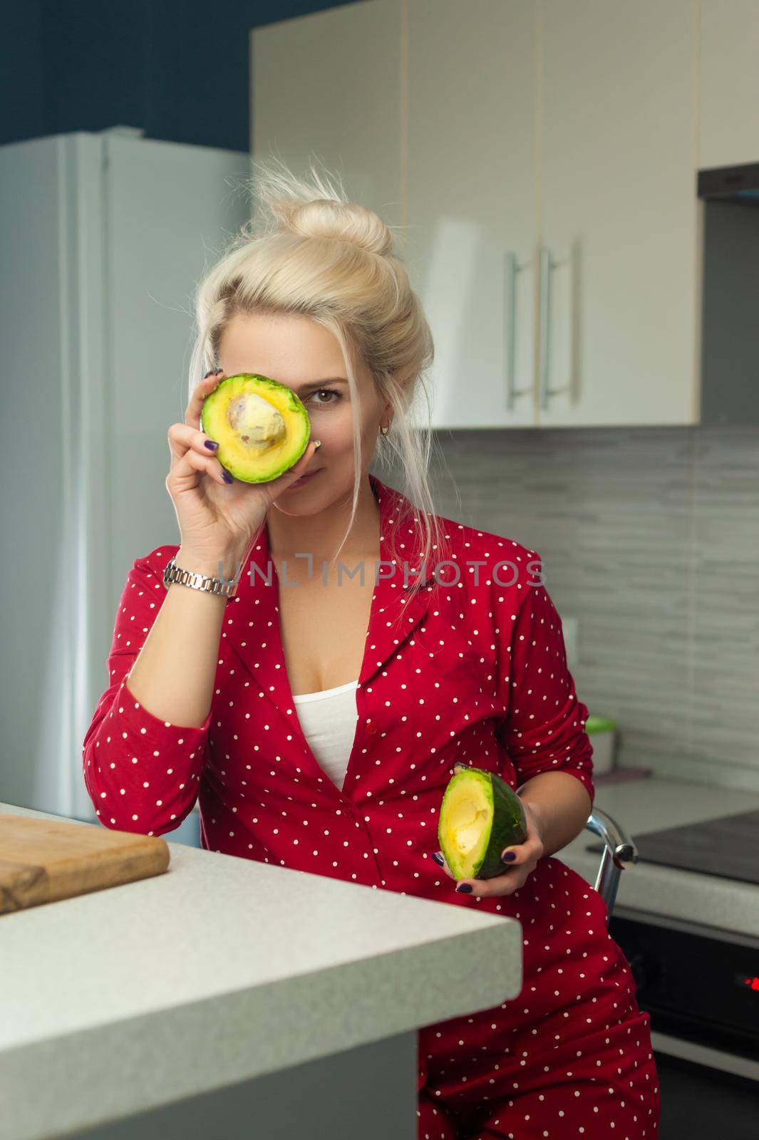 the blonde vegan woman cuts avocado in kitchen