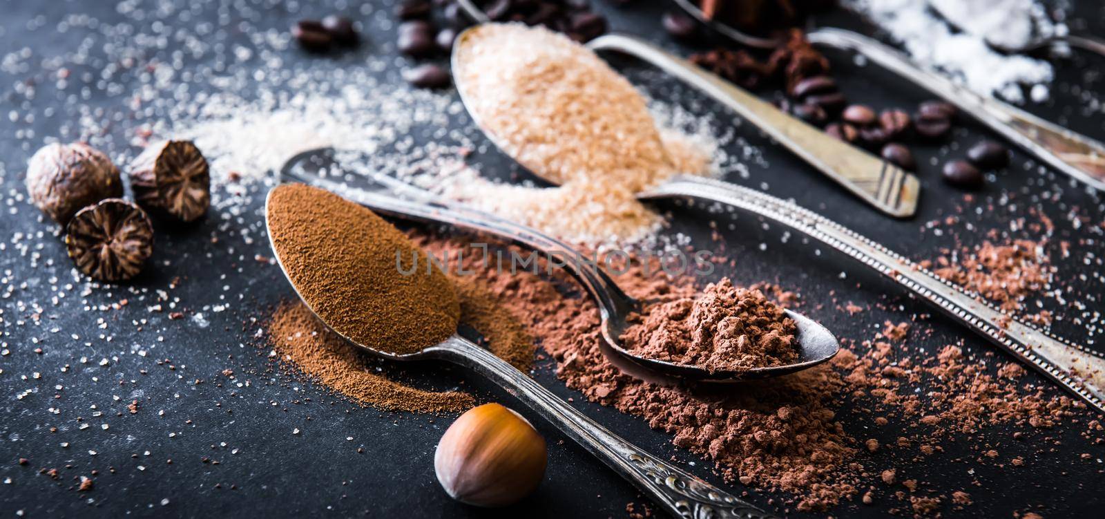 Chocolate powder cocoa and coffee spoons on the table black