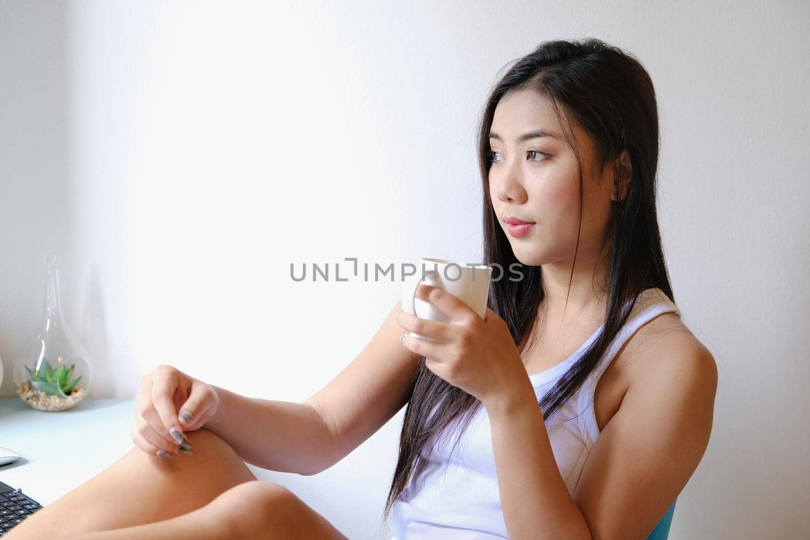 Smiling calm young woman drinking coffee at home