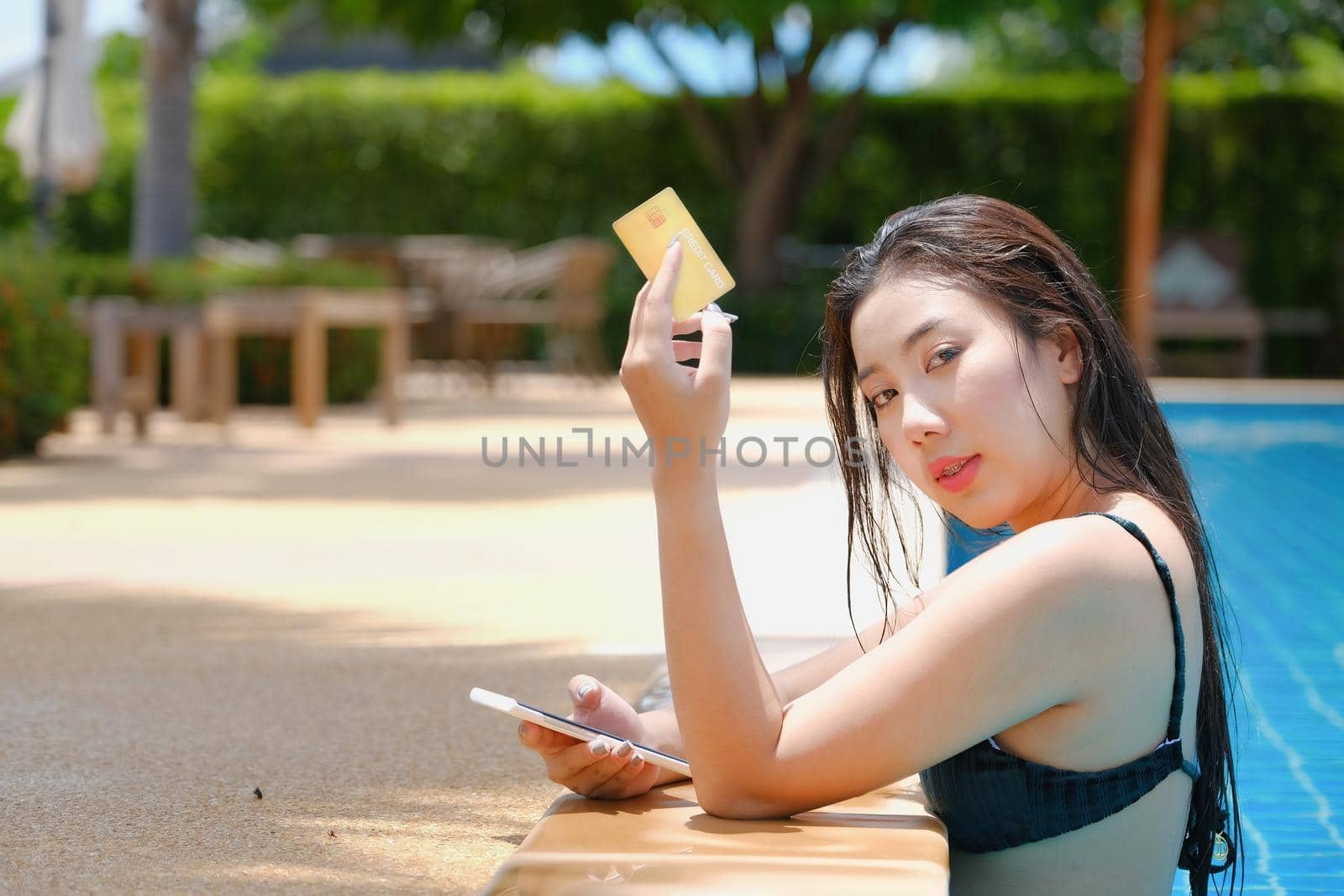 online payment, A teenage girl who swims is using her credit card with her phone to make purchases. online via internet. by Manastrong