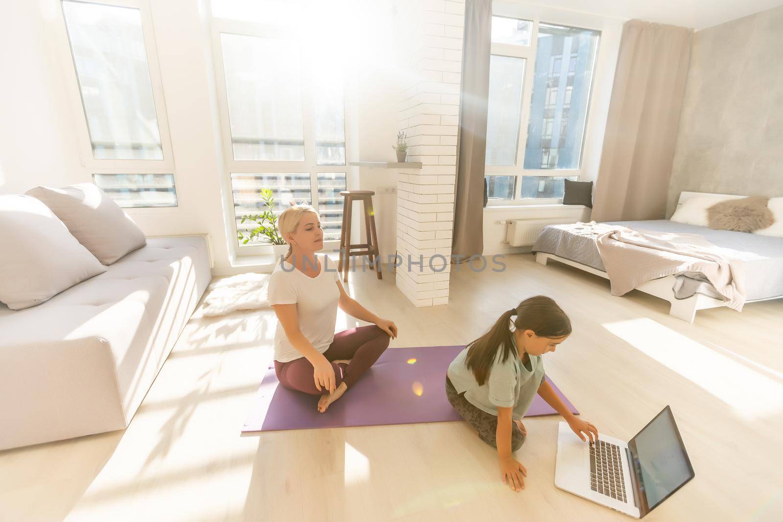 mother and daughter make yoga exercise online with laptop at home