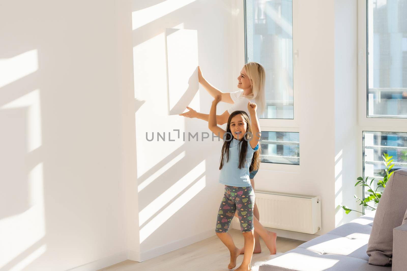 mother and daughter hold photo canvas at home