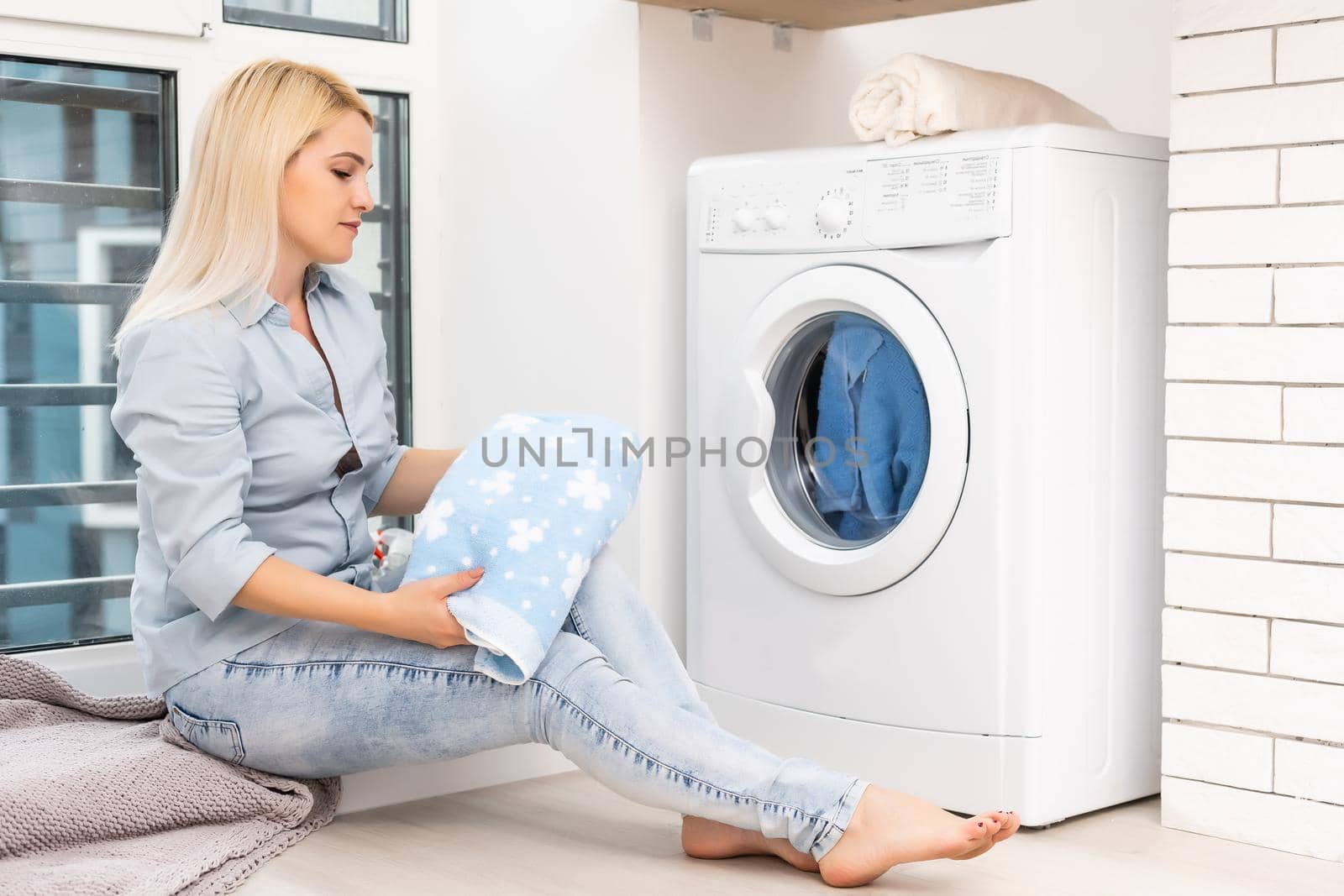 A young housewife with washing machine and clothes. Washing day.