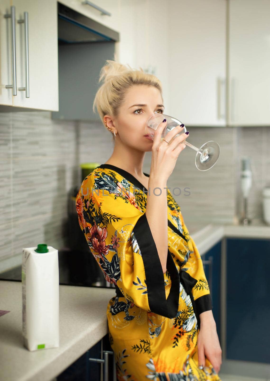 the Young clapboard in the kitchen with a pack of healthy natural juice drinks from a glass