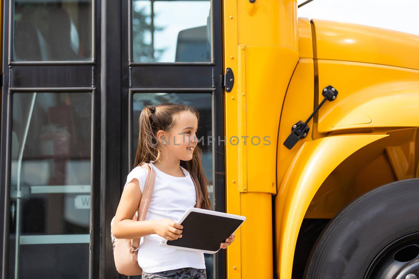 Girl with backpack near yellow school bus. Transport for students