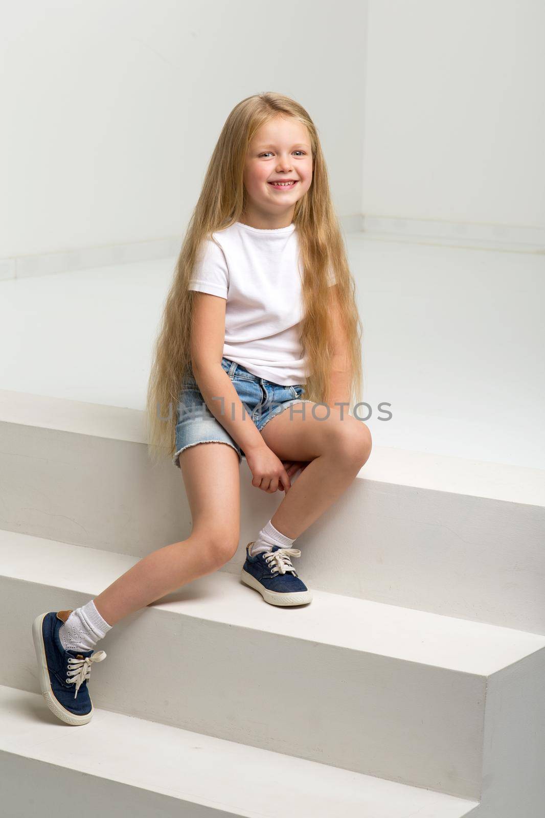 Girl in casual clothes sitting on white staircase by kolesnikov_studio