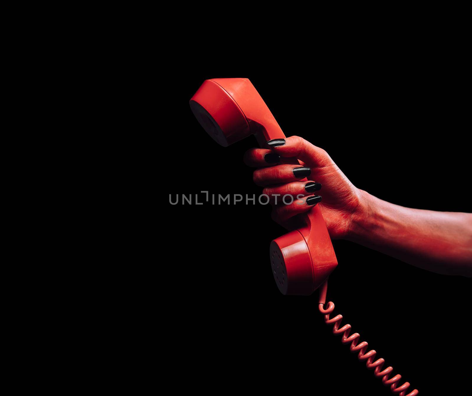 Red demon hand gives phone handset on dark background, space for text, Halloween or horror theme