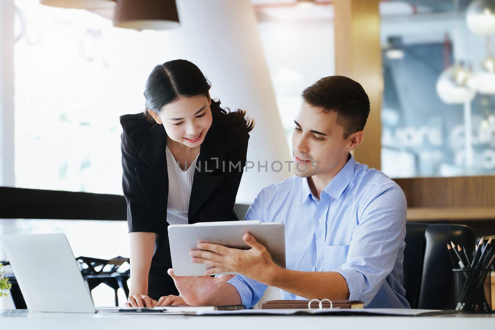 The male marketing manager expressed his satisfaction in selling the company's products. where team members show sales from their iPad screen