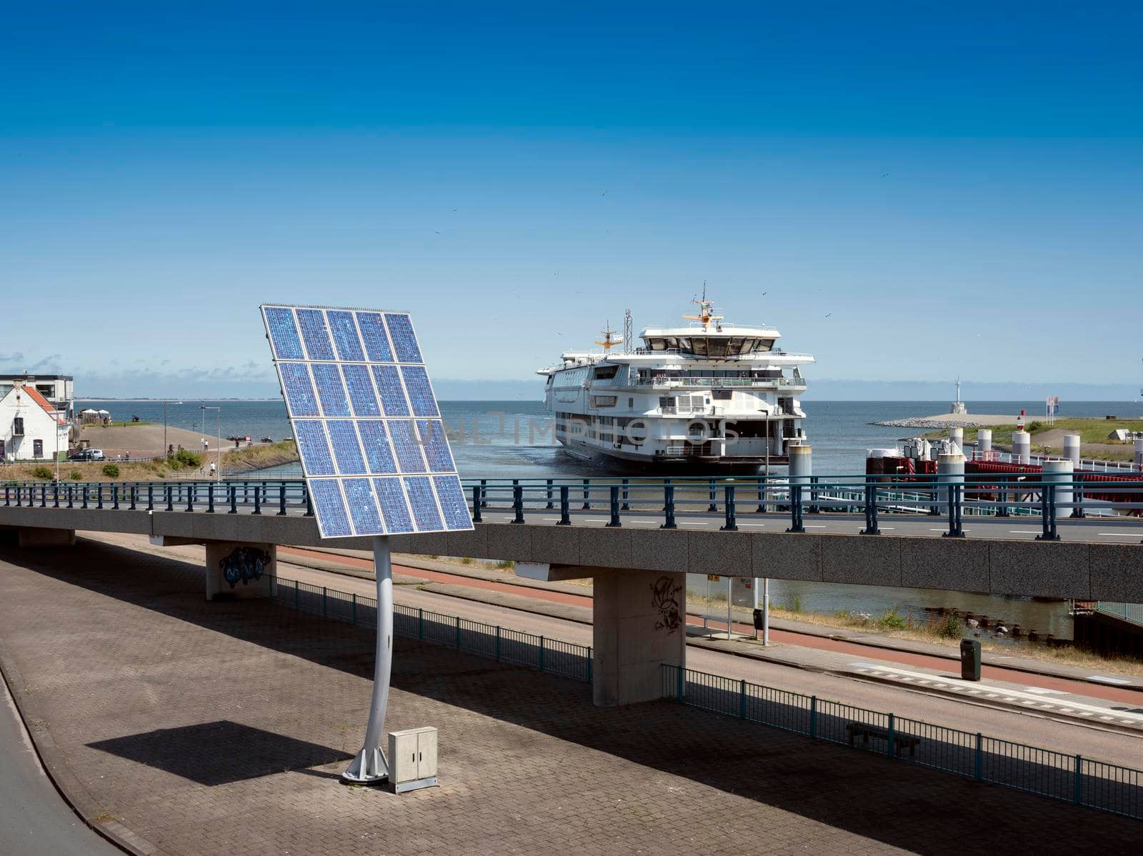 solar panels and arriving ferry from texel at port of den helder in the netherlands under blue sky on sunny summer day