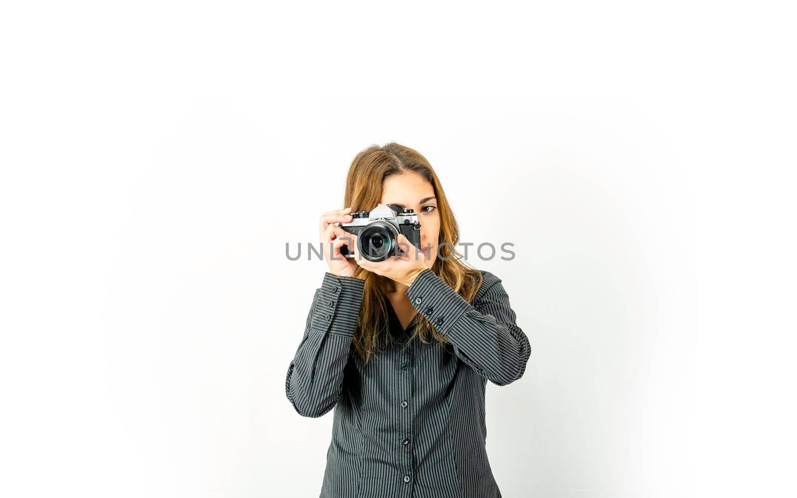 Beautiful young woman holding retro camera pointing subject and rotates focus ring on lens. Vintage versus new photography technologies at modern times. Large copy space for online photo courses adv by robbyfontanesi