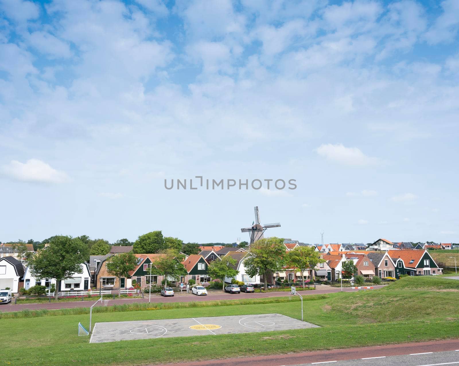 dutch village with windmill of oudeschild on dutch island of texel seen from ijsselmeer dike in summer