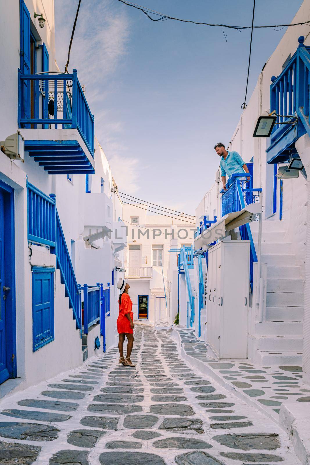 Mykonos Greece, Young man and woman in dress at the Streets of old town Mikonos during vacation in Greece, Little Venice Mykonos Greece by fokkebok