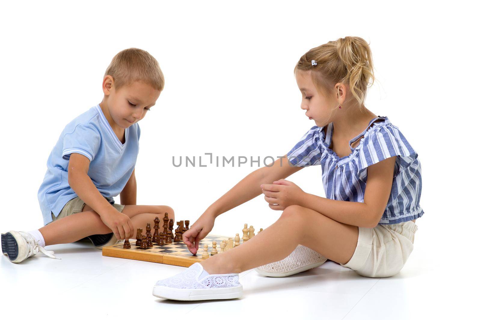 Couple boy and girl playing a board game of chess, thinking about the action and sitting on the floor. isolated on white background.