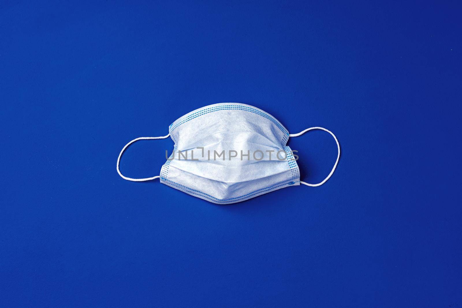 Medical face mask on blue background. Coronavirus covid-19 prevention concept