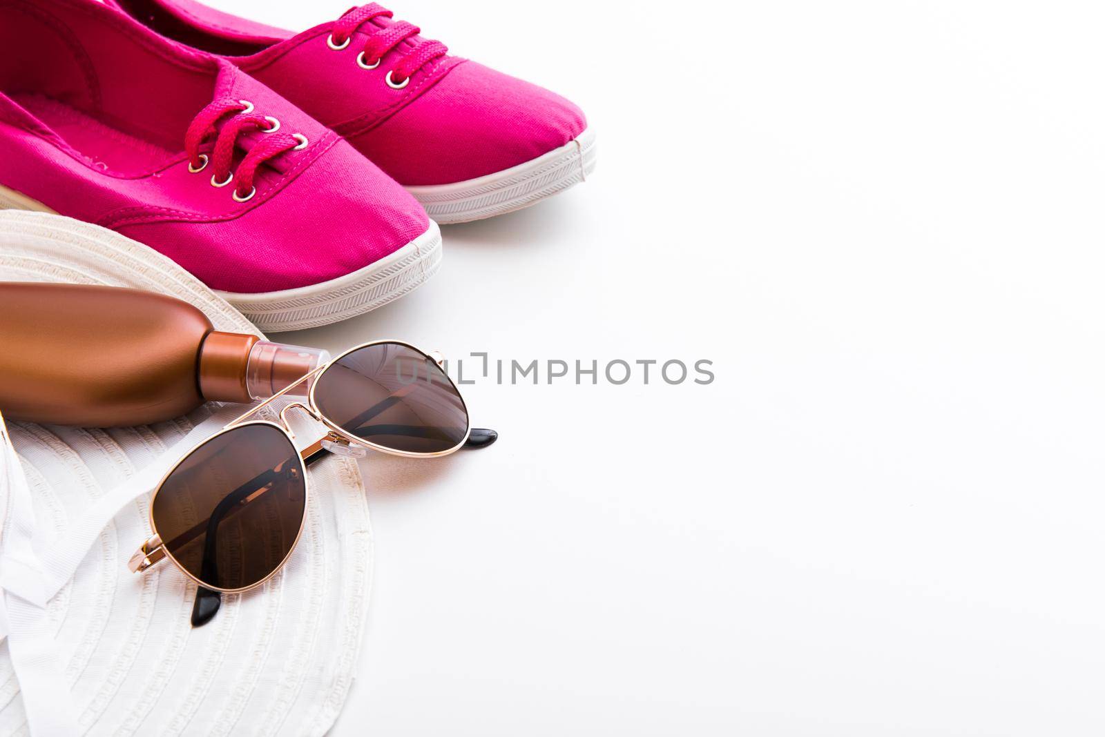 Beach accessories. Summer shoes and hat with sunglasses and suntan lotion on a white background