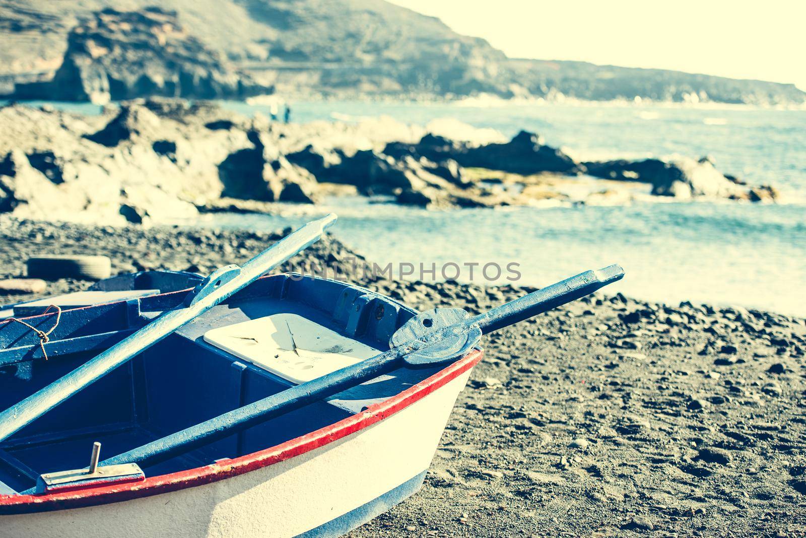 boat on a sandy shore on rocky coastline background