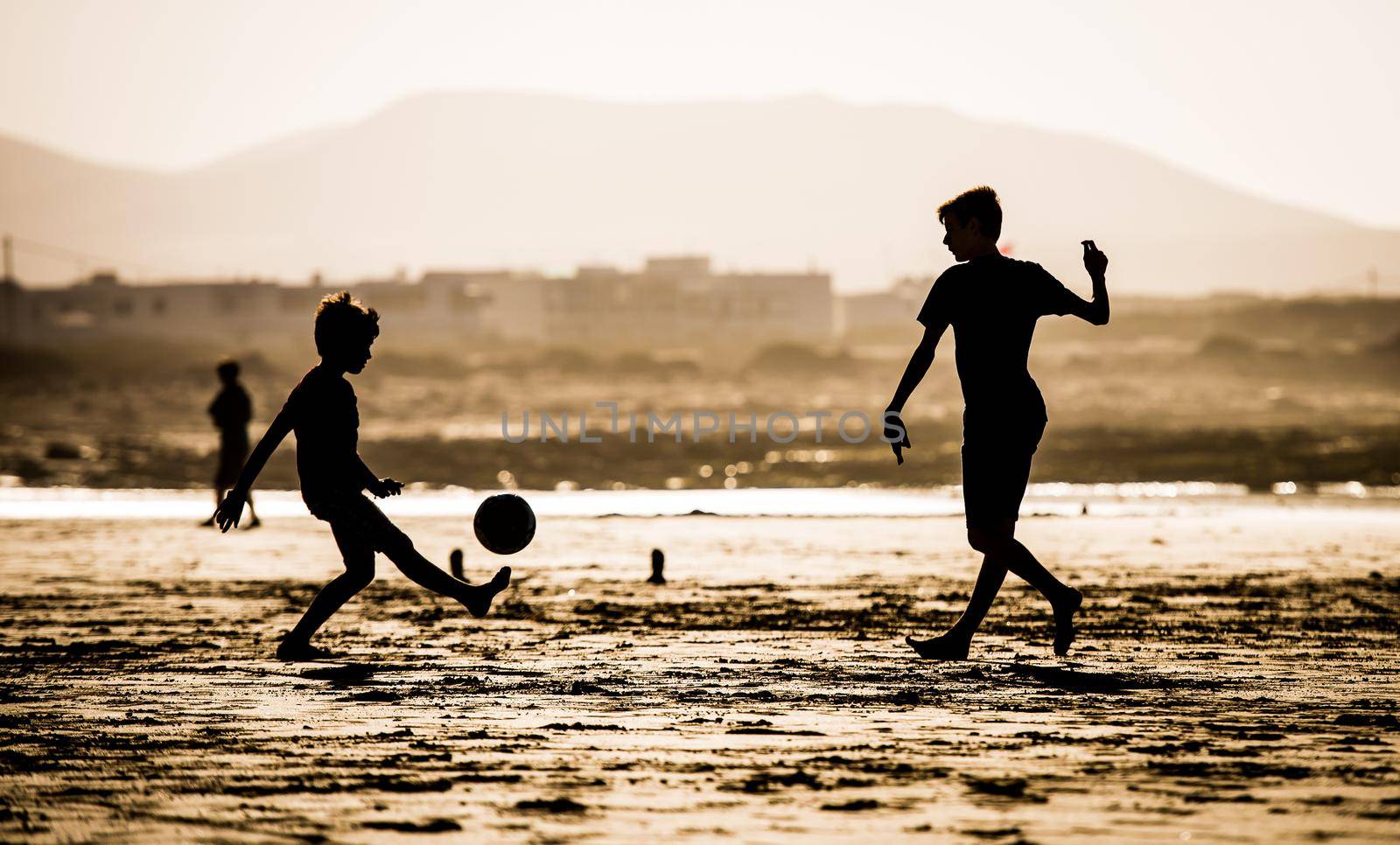 Silhouette of children on the beach with a ball