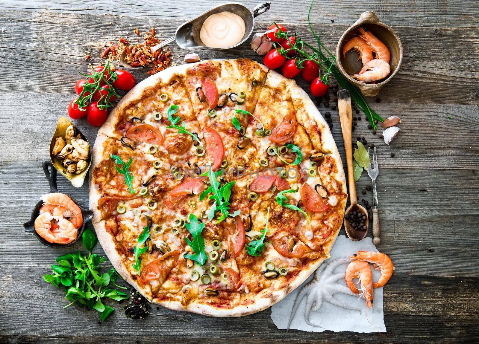 Big tasty pizza with seafood, tomatoes on a wooden table