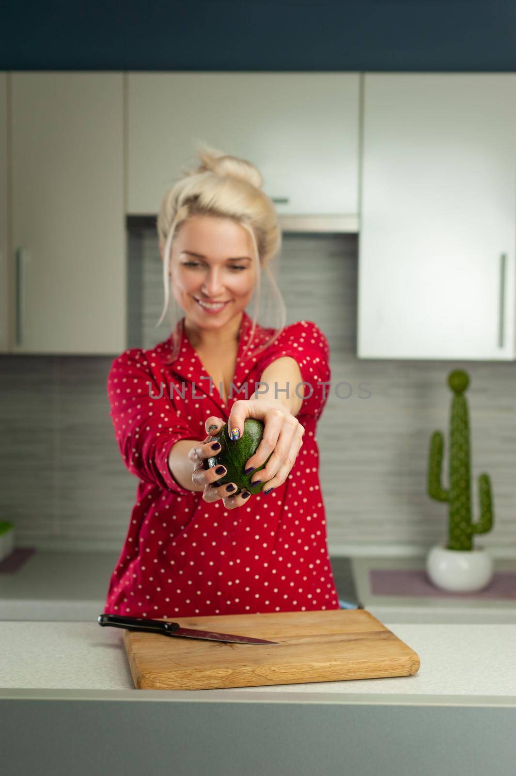 the blonde vegan woman cuts avocado in kitchen