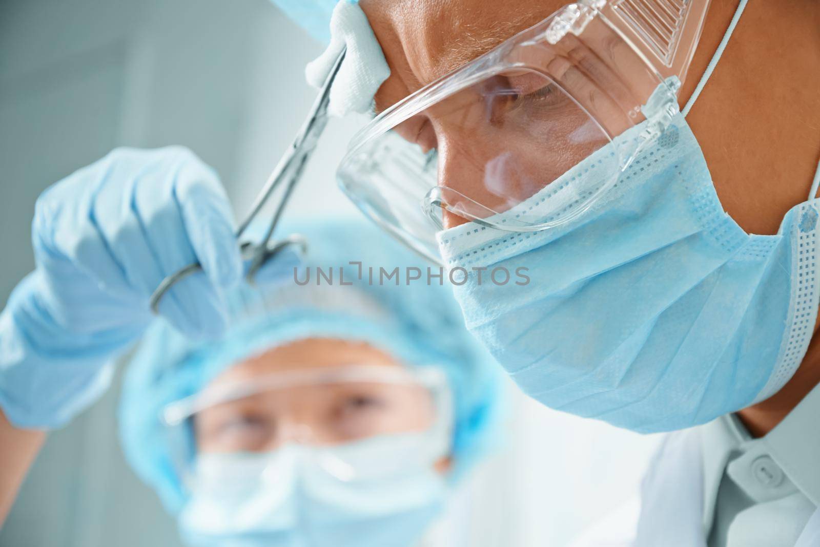 Nurse assistant rubs forehead of man surgeon on operation
