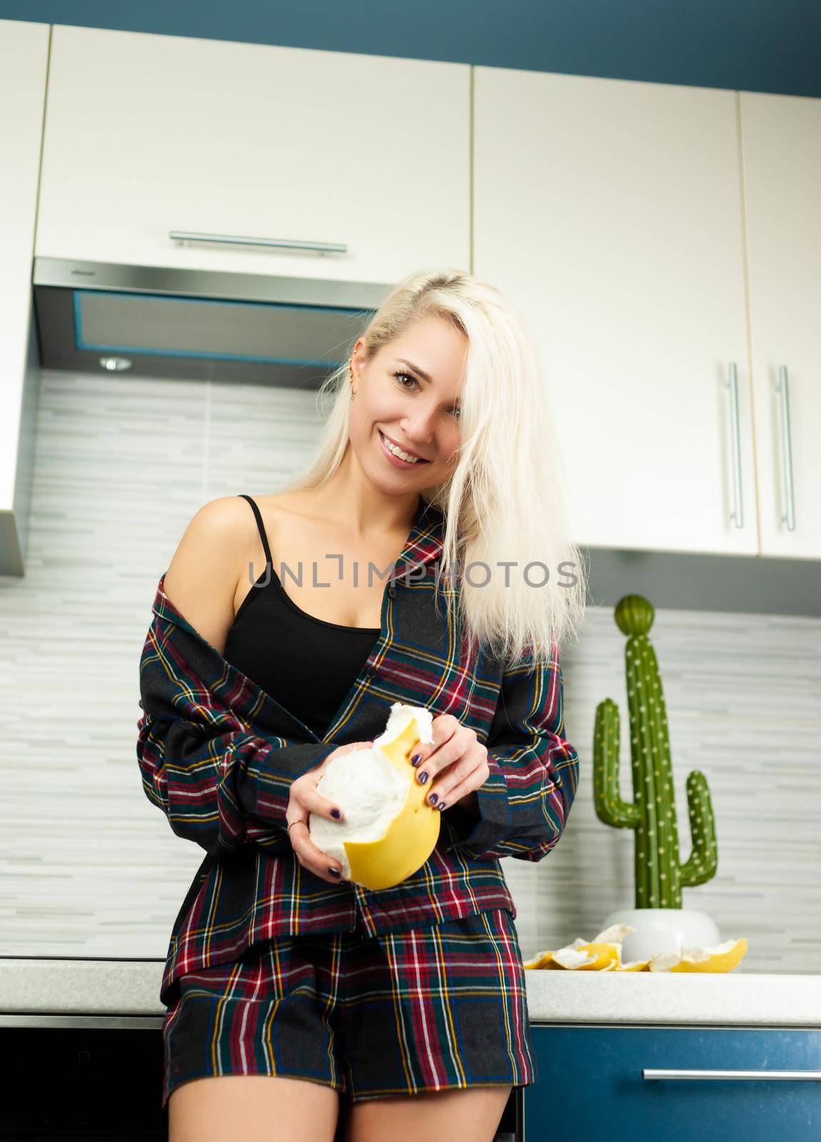 the Woman in the kitchen in home clothes cleaning fruit pomelo with emotions