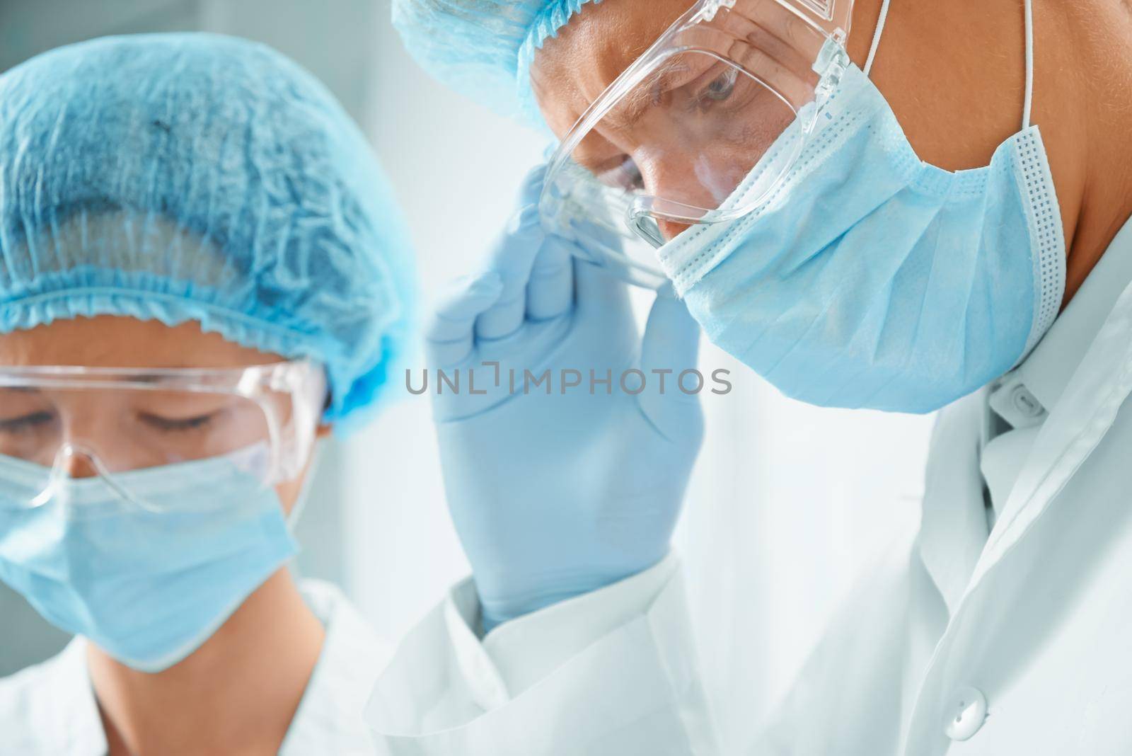 Woman and man surgeons in protective uniforms on operation