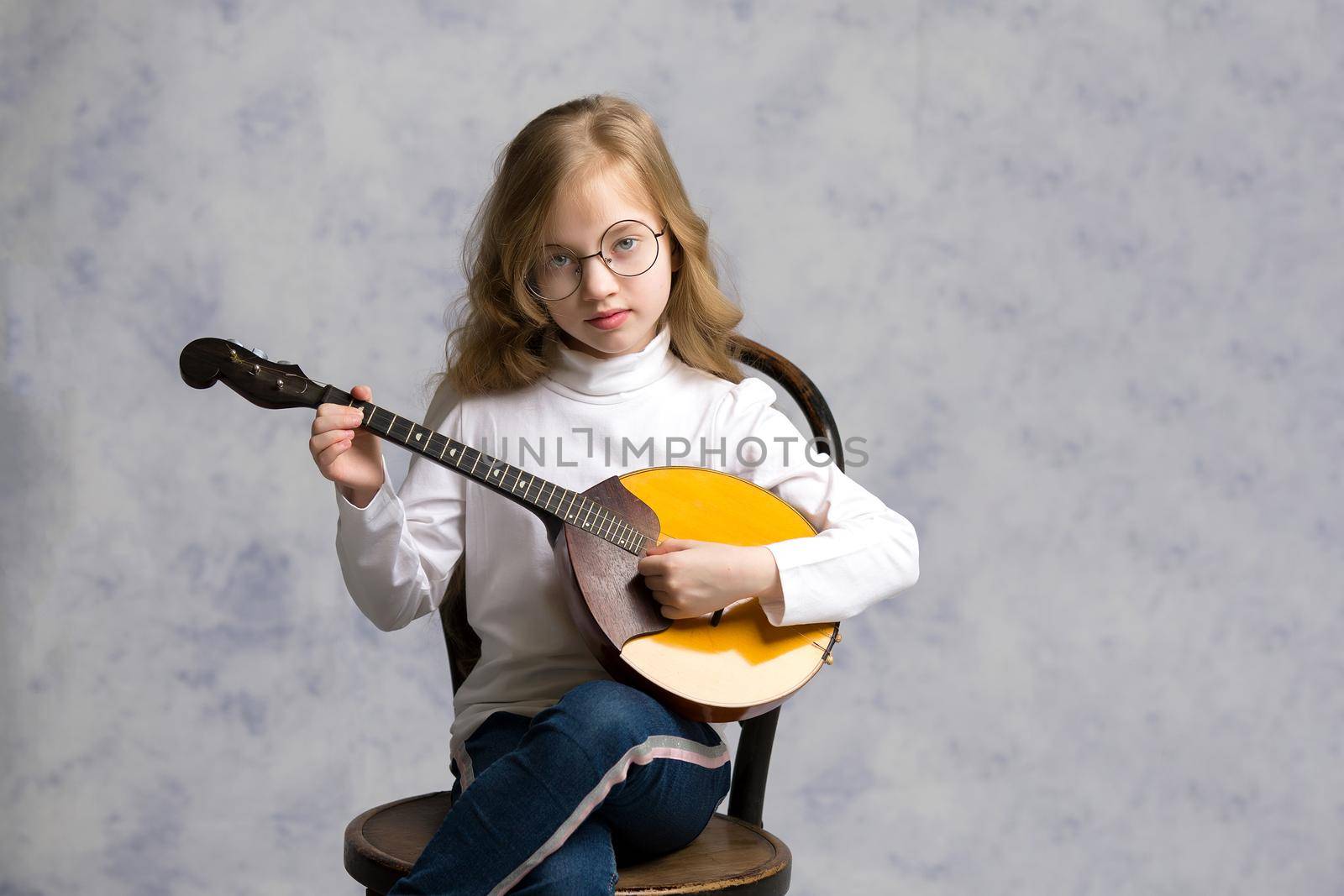Cute little girl learning to play the plucked musical instrument, domra.