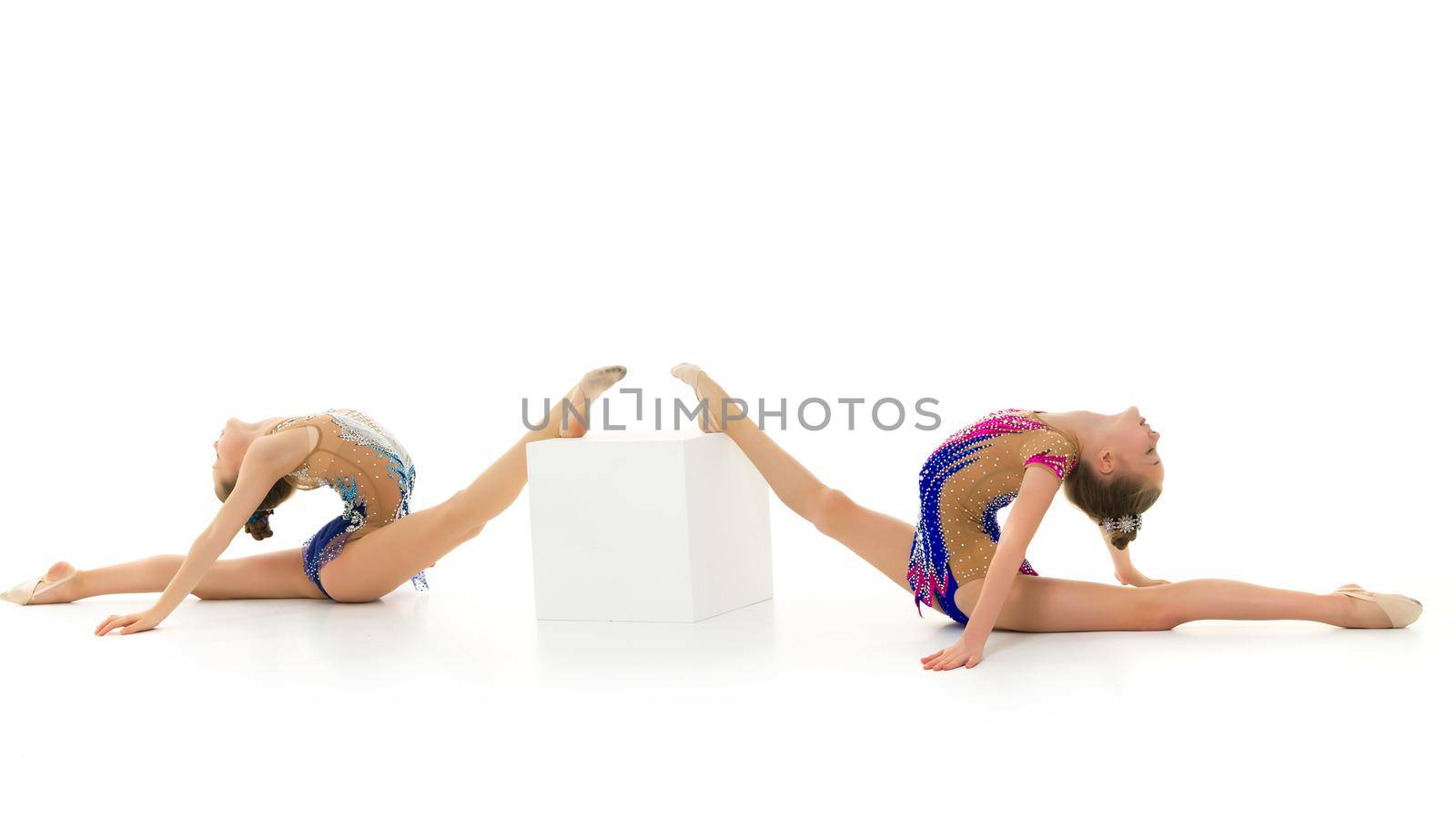 Two cute little girl gymnast in a beautiful sports swimsuit performs a gymnastic element, twine on Big White Cuba. Separately on a white background.
