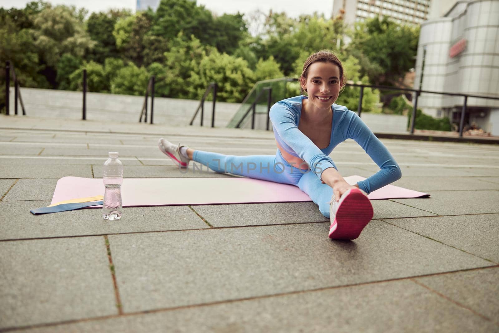 Beautiful fit caucasian woman is doing exercises outdoors at the city by Yaroslav_astakhov