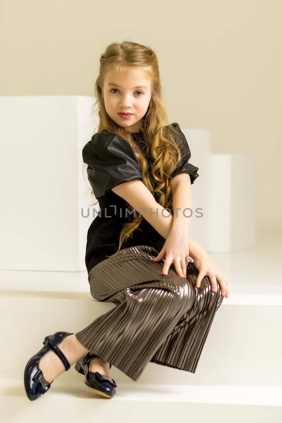 Little girl poses for a magazine in the studio on a white cube. by kolesnikov_studio