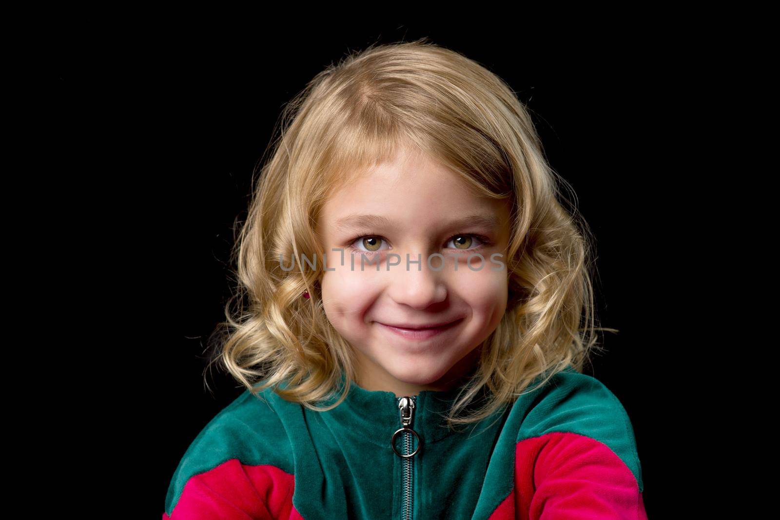 Close up view of a cute smiling girl, charming baby, wearing stylish clothes, posing in studio, portrait of a lovely happy girl, isolated on black background