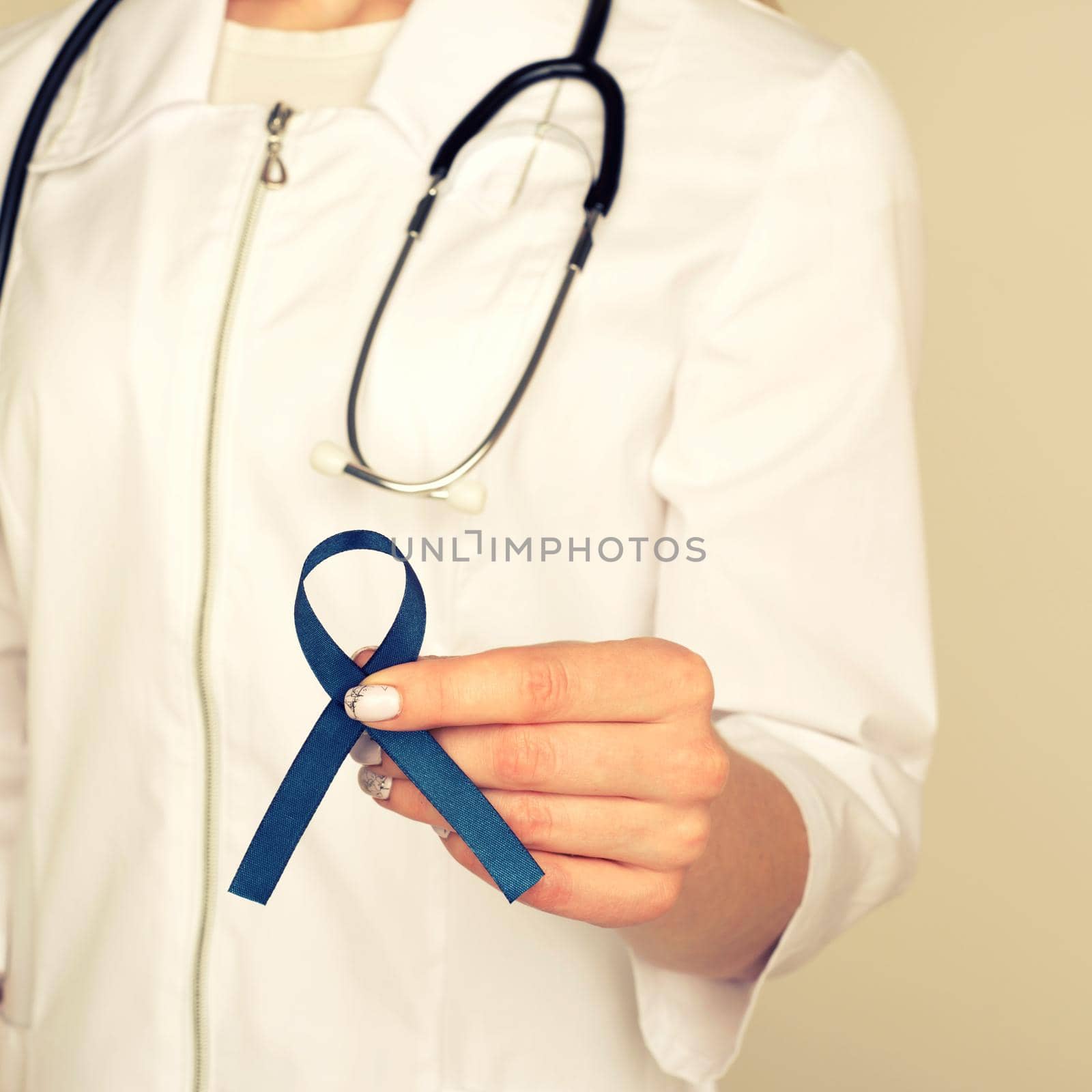 Doctor hands holding blue ribbon, diabetes and Colorectal Cancer Awareness by zartarn