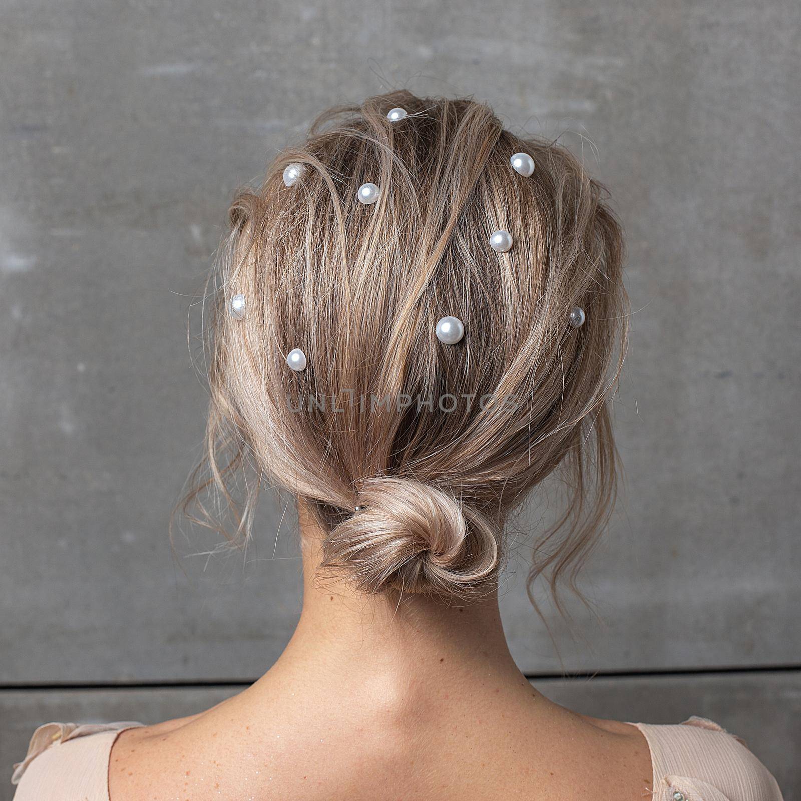 girl with pearl in hair against gray wall, rear view closeup. fashion hairstyle by artemzatsepilin