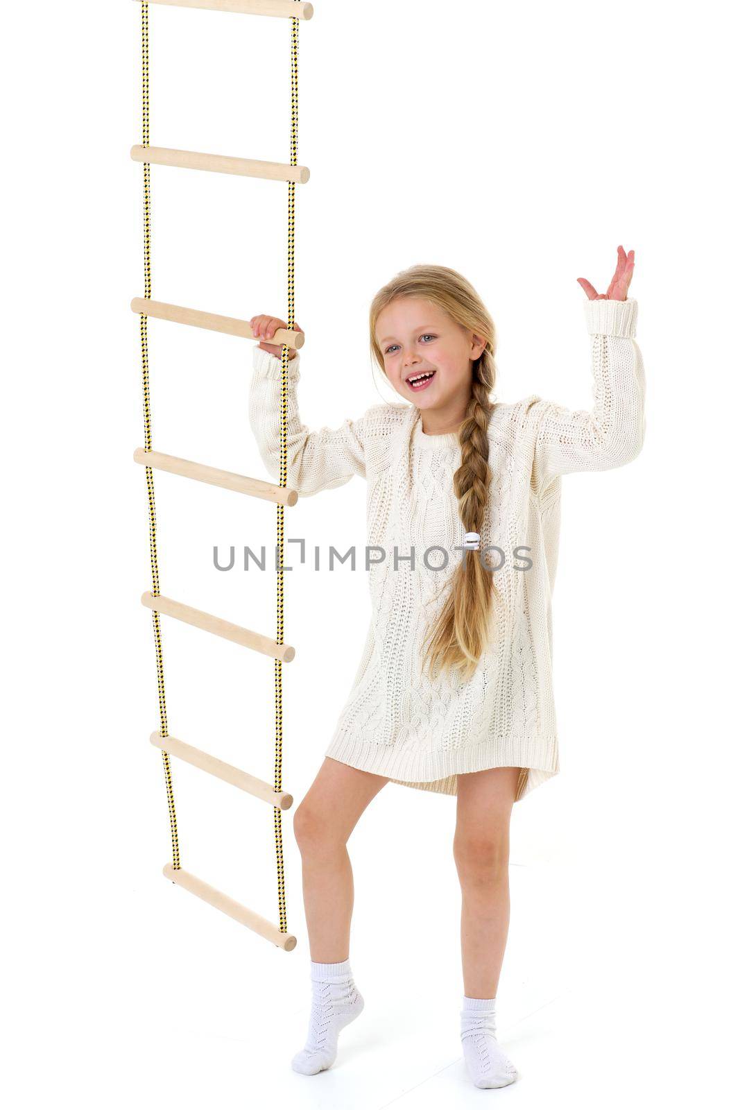 The girl climbs the rope ladder. Cheerful child on a white background. Active healthy lifestyle concept