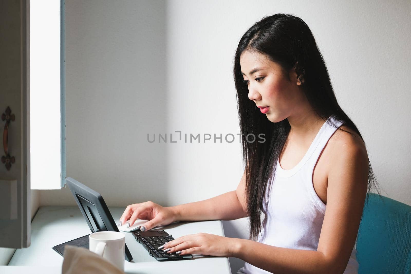 new normal era, A female company employee uses a tablet to work from home due to the coronavirus situation.. by Manastrong
