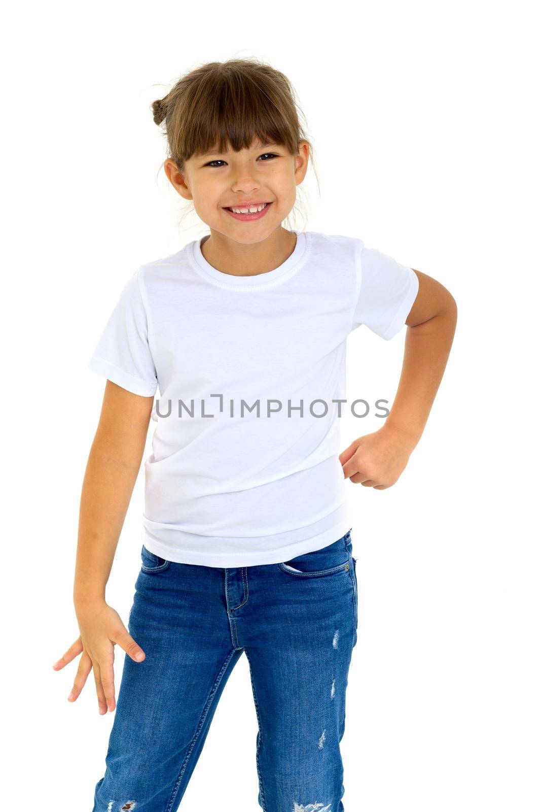 Cute angry girl with hands on her waist. Adorable little girl dressed white t-shirt and jeans posing on isolated white background. Beautiful child with serious face expression